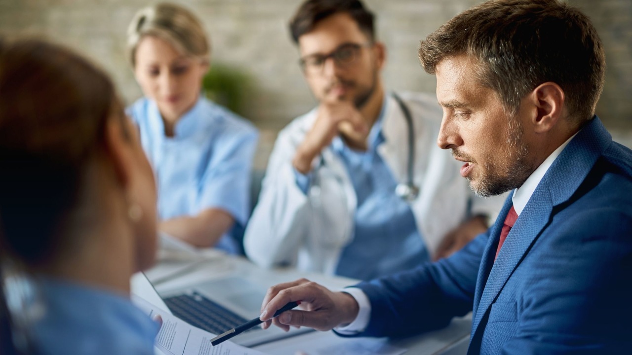 Equipe médica conversando em sala de reunião. Imagem simboliza que o time está discutindo as vantagens e desvantagens das glosas.